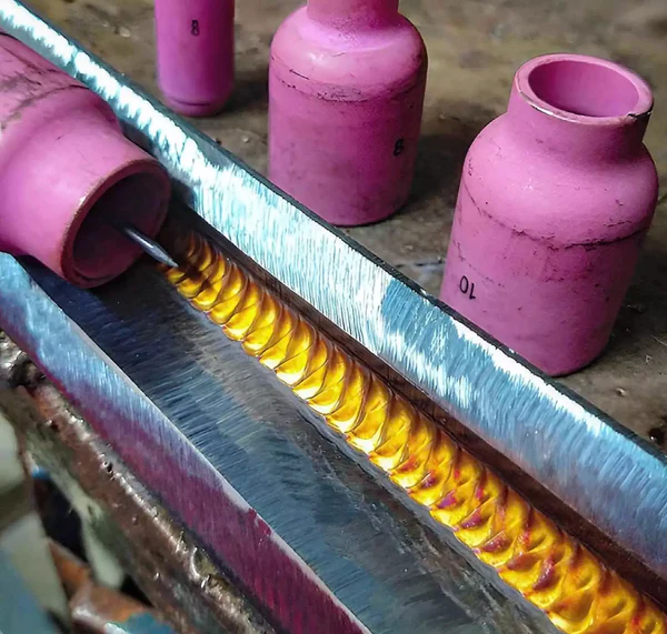 Image of a Tig Torch welding on metal with three gas cups in the background