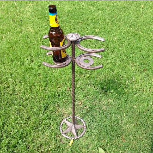 An image of four horse shoes welded onto a metal bar that has been mounted onto a base for the footer to make the cup holder