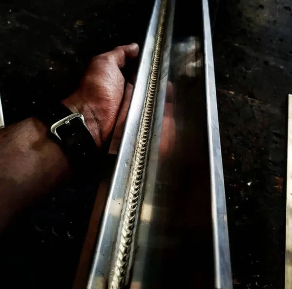 Image of a hand holding a newly finished welded steer bar