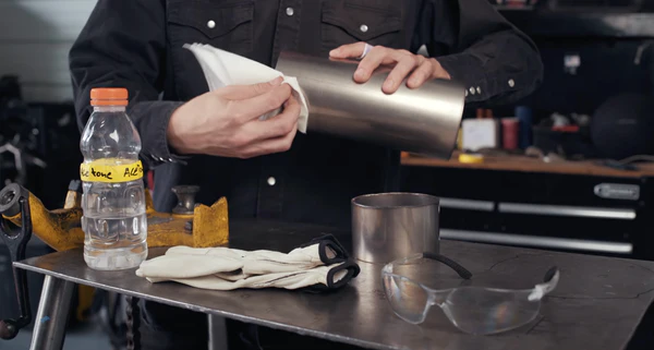 Image of a welder using acetone and a clean, lint-free cloth to wipe the titanium joint