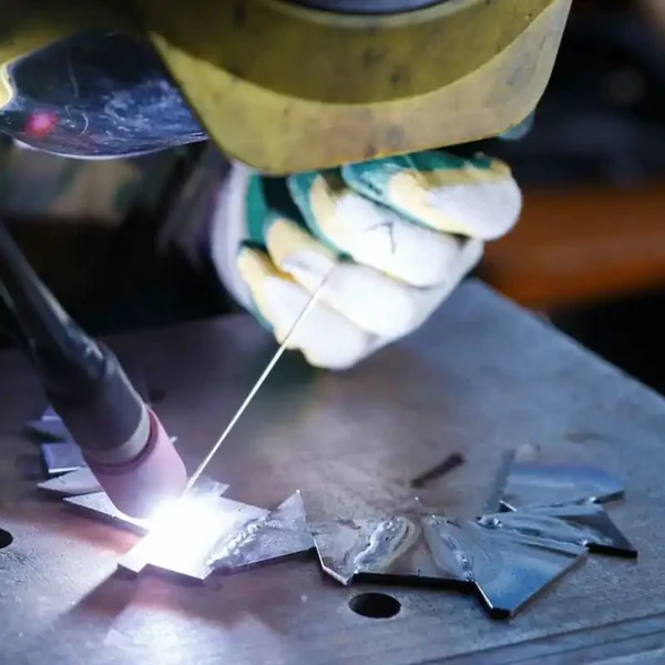 Image of a welder welding pieces of scrap metal together using hydrogen gas