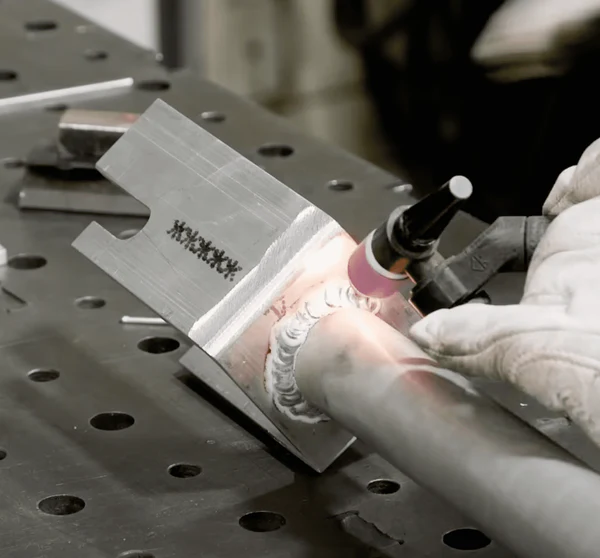 Image of a metal cylinder being welded to a metal box using helium gas